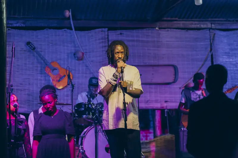 Un chanteur au micro, entouré de ses musiciens, lumière violette
