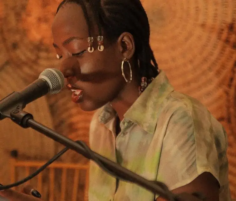 Une jeune chanteuse travaille au micro, lumière orangée