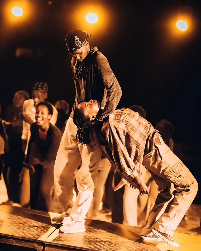 Deux danseurs, l'un plié sous l'autre, sur la scène