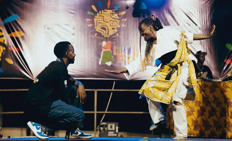 Un danseur en tenue traditionnelle face à un danseur accroupi