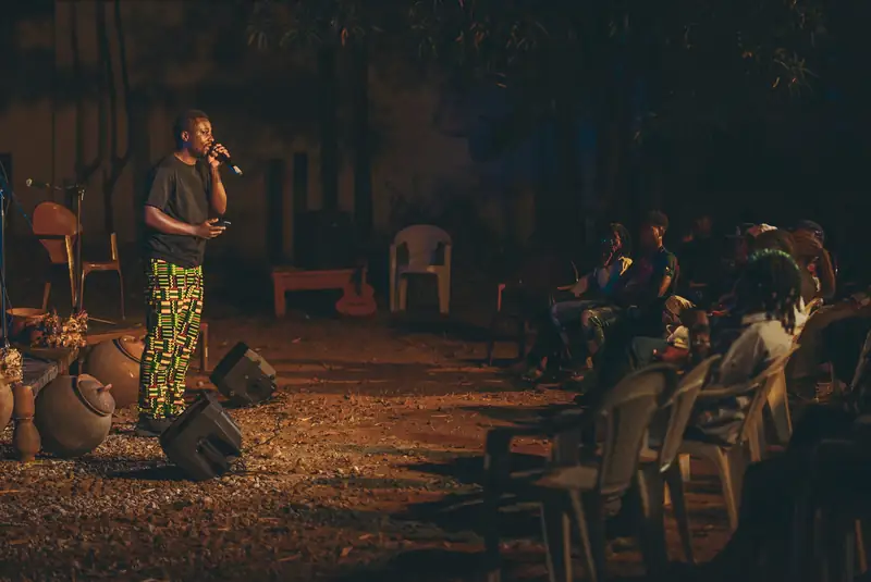 Un slameur au micro dans le jardin, la nuit